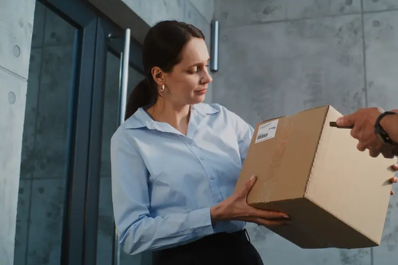 Frau nimmt an der Tür ein Paket vom Paketboten entgegen