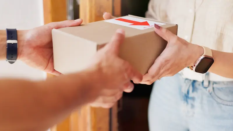 Ein Paket wird an der Haustür von einer Hand in die andere übergeben